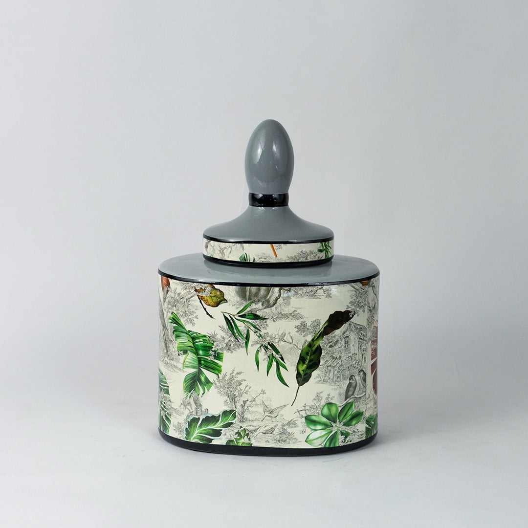 Tropical leaf jar on plain white background with vivid green leaf design and smooth ceramic finish.