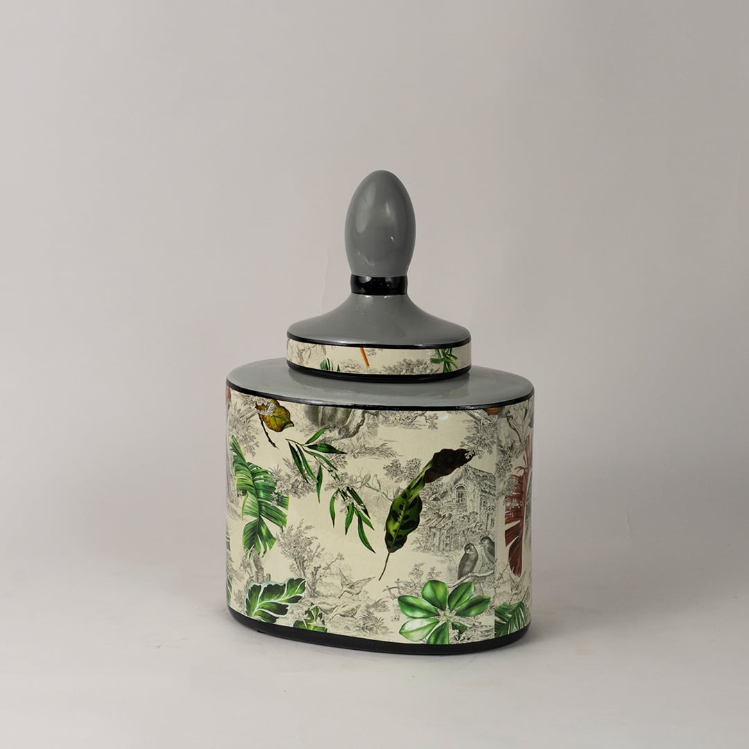 Side angle of tropical leaf jar showing curved body and tropical botanical artwork with glossy surface.