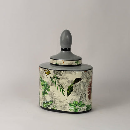 Side angle of tropical leaf jar showing curved body and tropical botanical artwork with glossy surface.