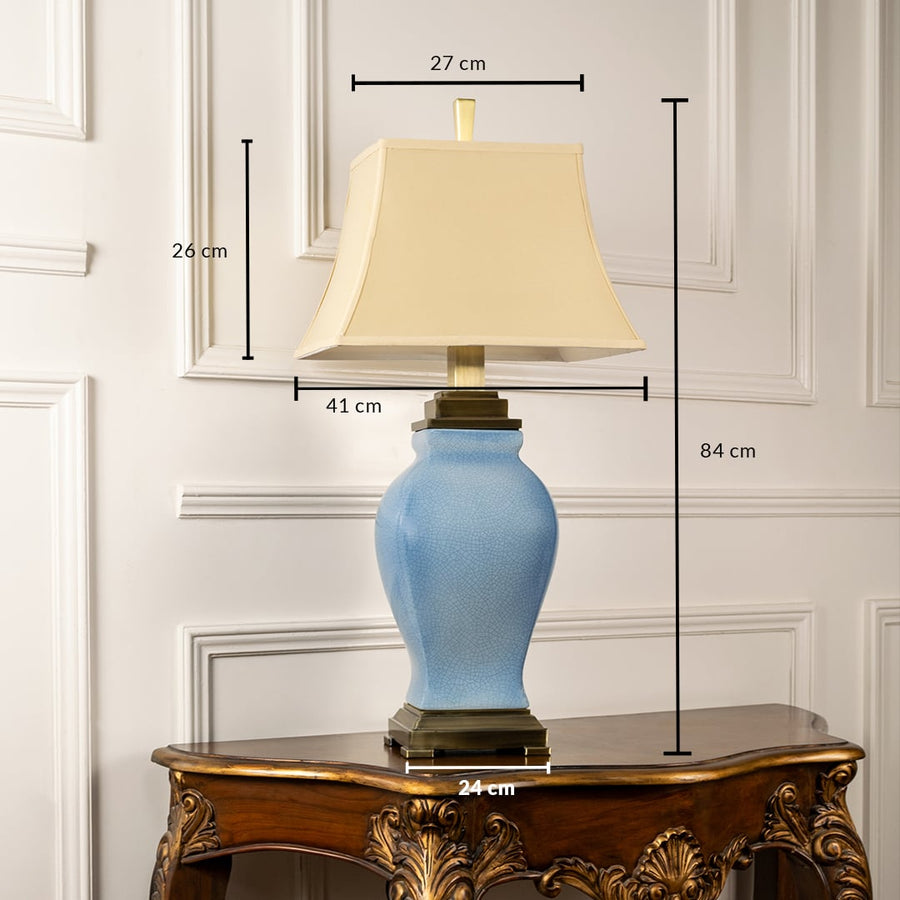 Cream shade blue ceramic table lamp with size 72cm height and 37cm width on carved console table with light on for classic elegant décor.