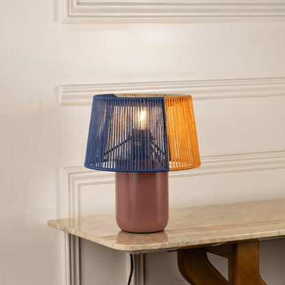 Table lamp with dual color fabric shade and ceramic base ideal for modern bedroom or living room decor on clean background.