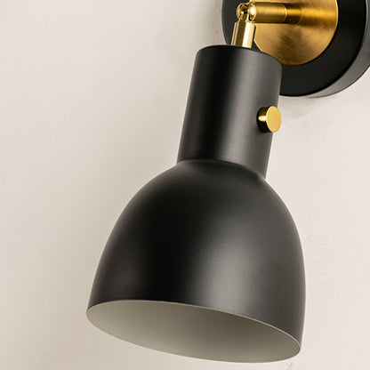 Closeup of gold metal wall light with smooth cone shade for elegant bedroom hallway and modern home decor styling.