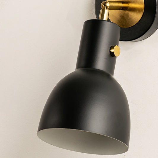 Closeup of gold metal wall light with smooth cone shade for elegant bedroom hallway and modern home decor styling.