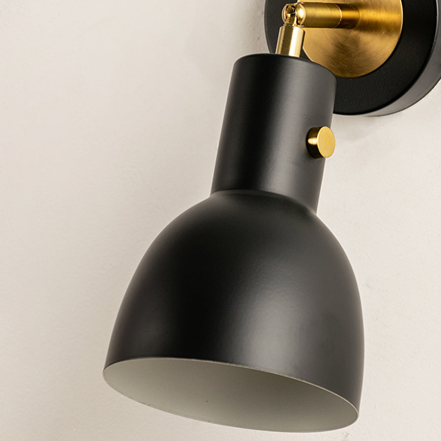 Closeup of gold metal wall light with smooth cone shade for elegant bedroom hallway and modern home decor styling.