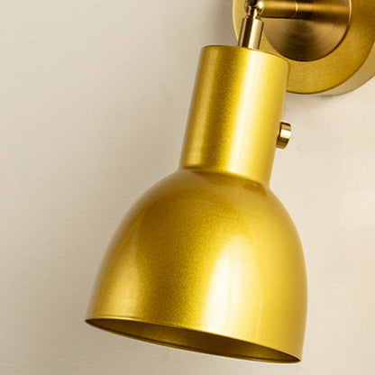 Closeup of gold metal wall light with smooth cone shade for elegant bedroom hallway and modern home decor styling.
