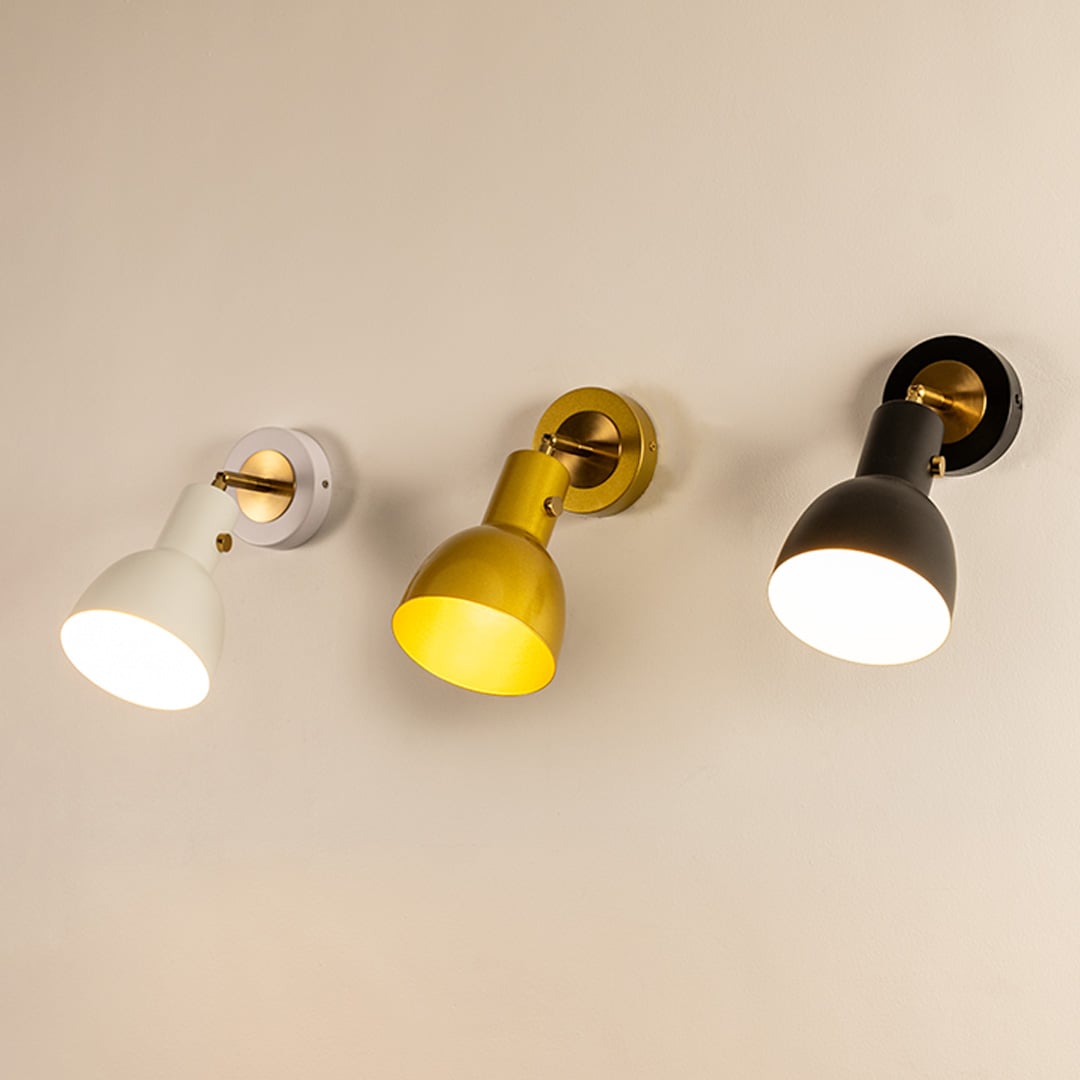A set of glowing white gold and black metal wall lights displayed on a soft beige wall creating warm lighting and enhancing modern sconce décor in interior spaces.