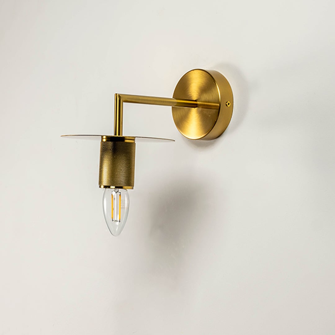 Gold wall sconce with round shade displayed off on white background ideal for contemporary bedroom or hallway decor.