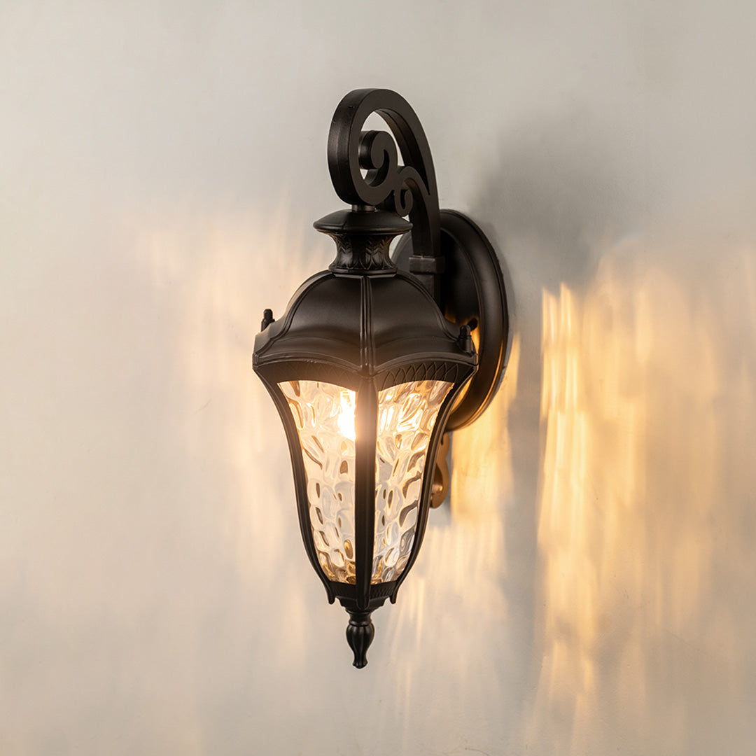 Antique bronze metal outdoor wall light on white background with textured glass casting a bright warm glow for decor.