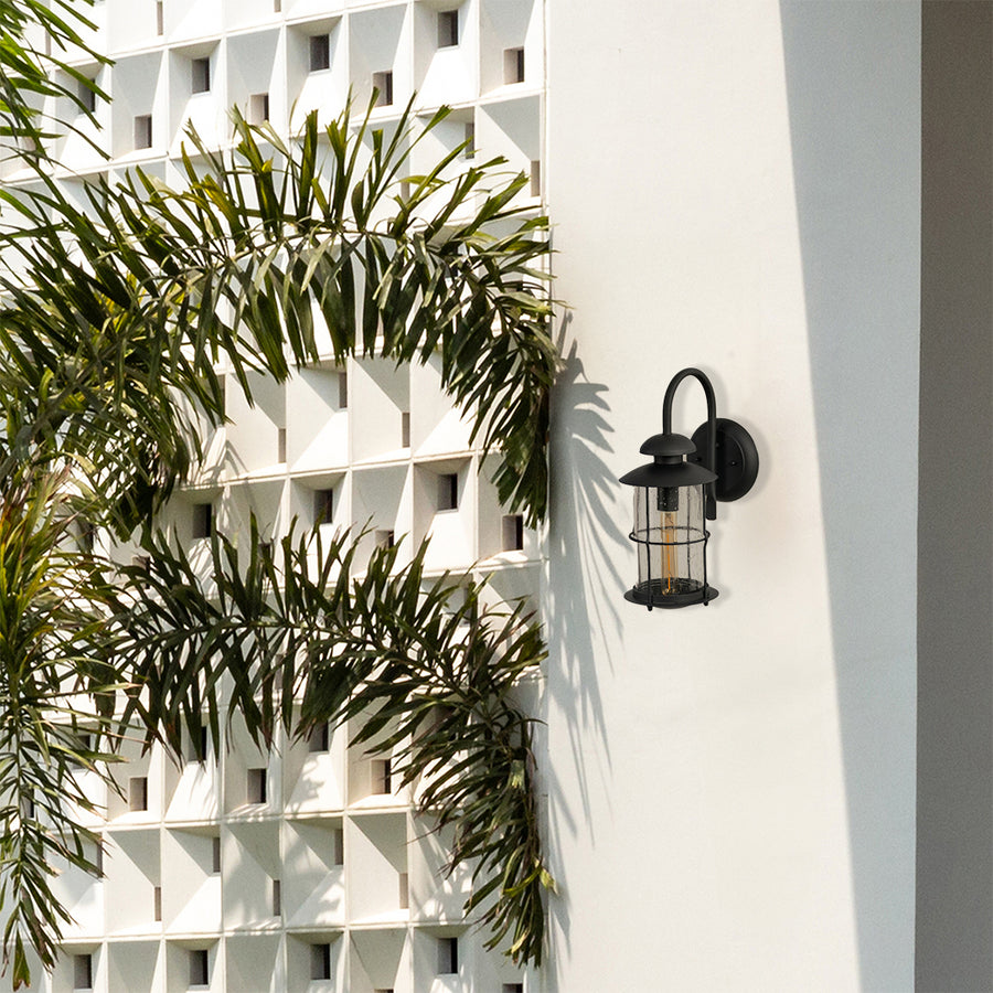 Modern black outdoor lantern styled in a minimal setting showing its clear raindrop glass and elegant curved arm shape.