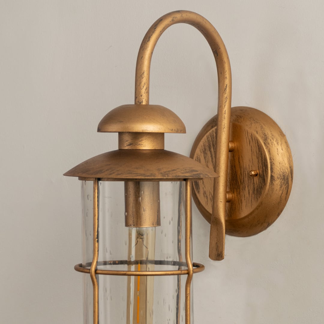 Industrial brass gooseneck outdoor wall light closeup image showing textured metallic finish and clear glass cylinder shade.
