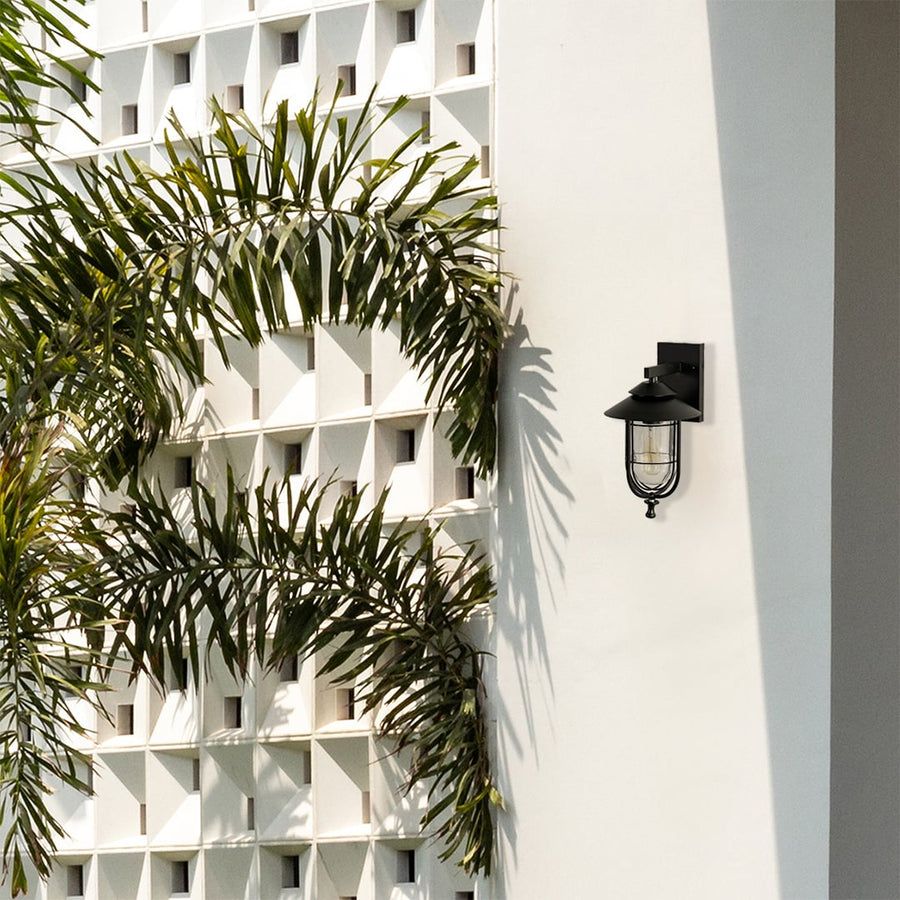A sleek black wall light mounted on a bright exterior wall enhancing the outdoor space with a clean modern aesthetic highlighted by patterned structures and greenery.