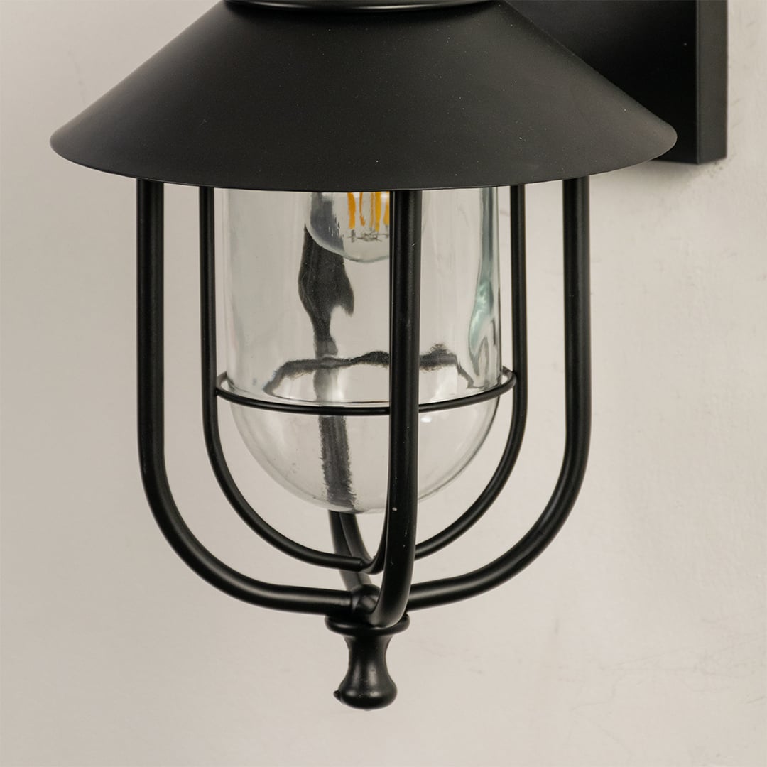 Close view of the black outdoor lantern showing detailed metal curves clear glass housing and refined modern finish.