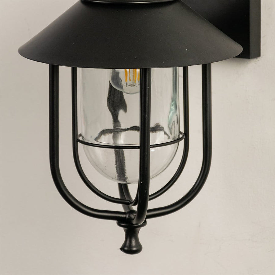 Close view of the black outdoor lantern showing detailed metal curves clear glass housing and refined modern finish.