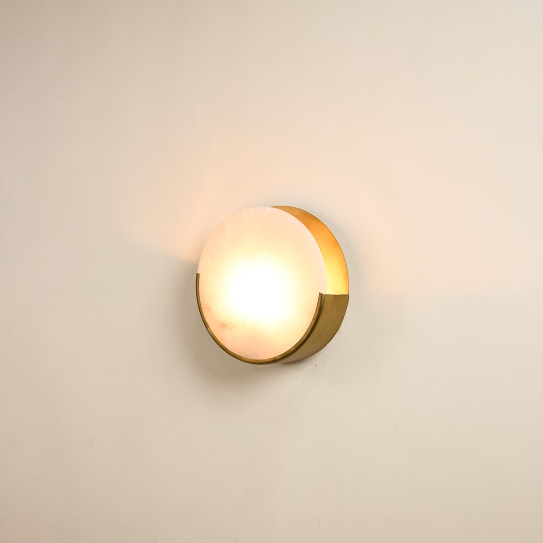Elegant marble wall sconce with golden base illuminated on white background showcasing timeless beauty perfect for modern and classic decor.