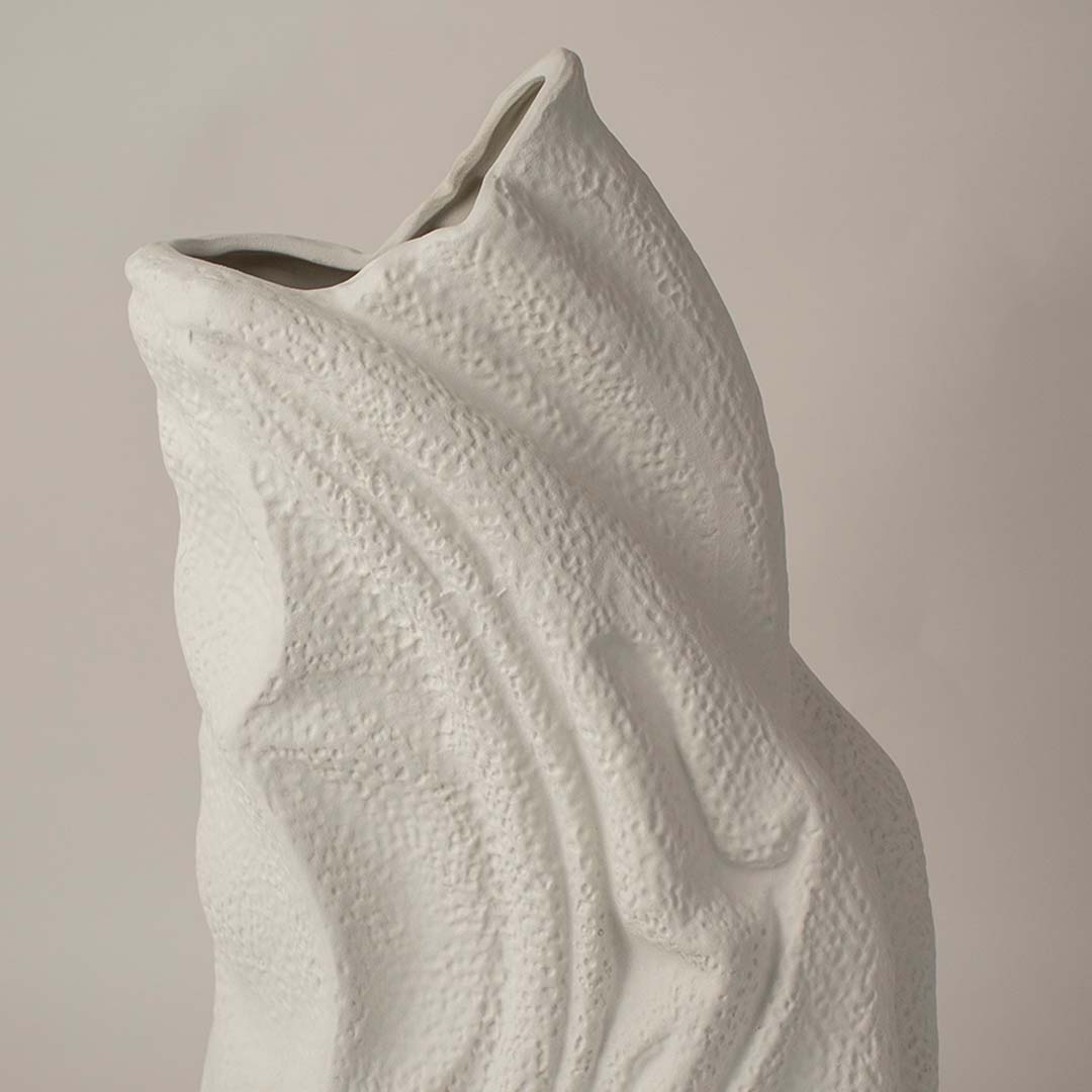 White sculptural ceramic vase closeup highlighting flowing textured surface and handcrafted organic form for contemporary interior styling.