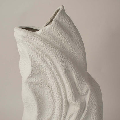 White sculptural ceramic vase closeup highlighting flowing textured surface and handcrafted organic form for contemporary interior styling.