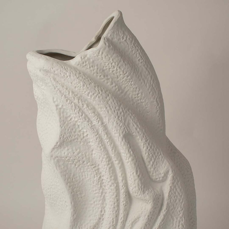 White sculptural ceramic vase closeup highlighting flowing textured surface and handcrafted organic form for contemporary interior styling.