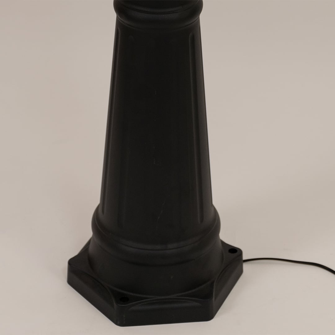 Detailed close up of black metal post lamp base showing textured pole construction decorative rings and mounting foundation design.