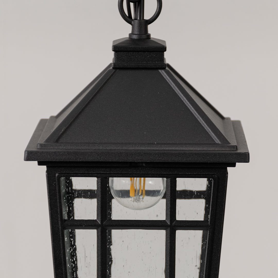 Closeup of black metal outdoor lantern light with clear glass panels on white background suitable for gate and pathway decor.