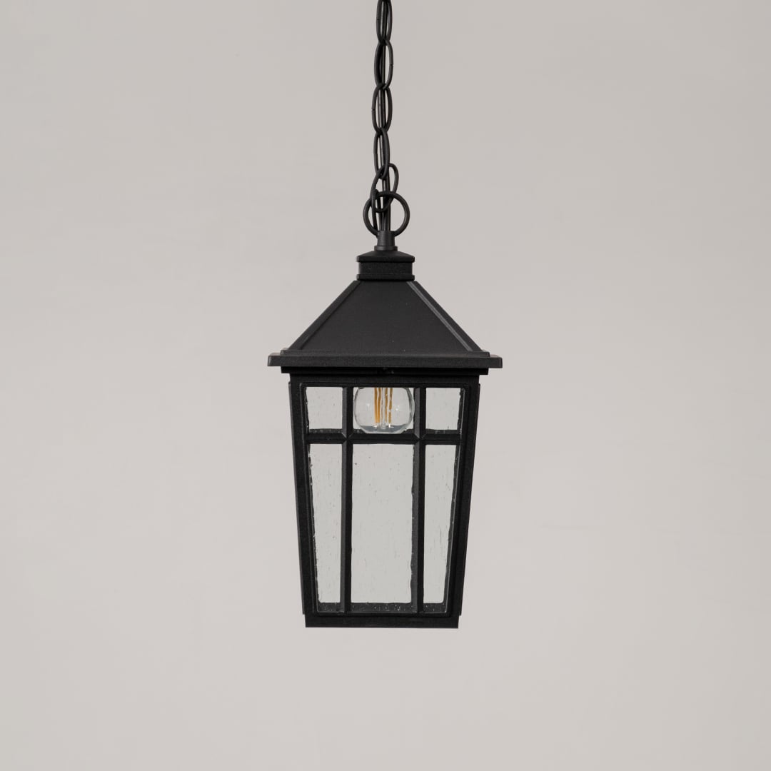 Traditional black hanging lantern with clear glass and chain suspension switched off displayed on minimal white backdrop.