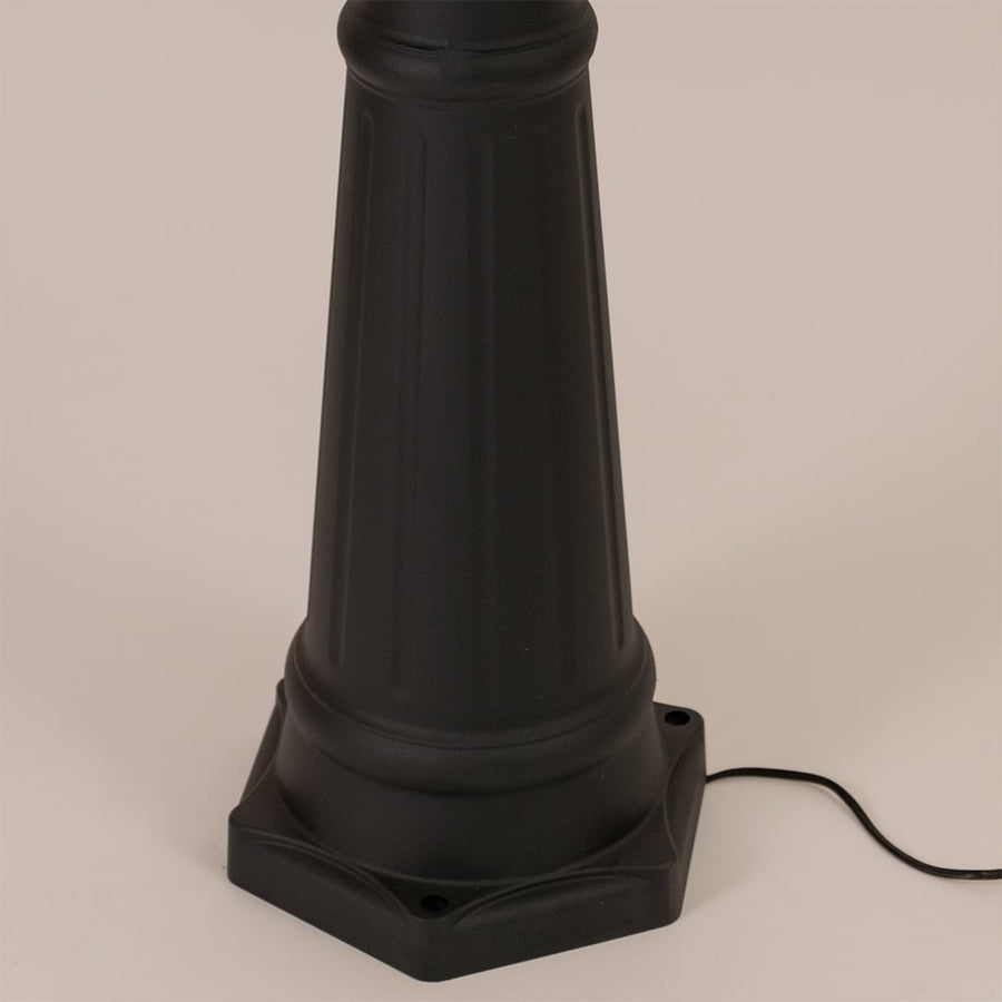Detailed close up of black metal post lamp base showing textured pole construction and decorative mounting foundation design.