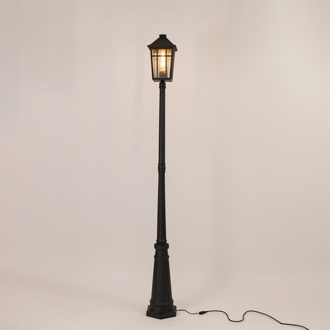 Decorative black outdoor street lamp with warm glowing lantern for luxury exterior decor use.
