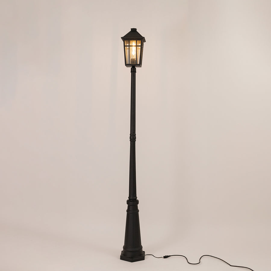 Decorative black outdoor street lamp with warm glowing lantern for luxury exterior decor use.