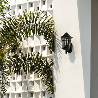 A classic black clear glass outdoor lantern mounted on a bright white exterior wall enhancing architectural design and adding stylish outdoor lighting appeal.
