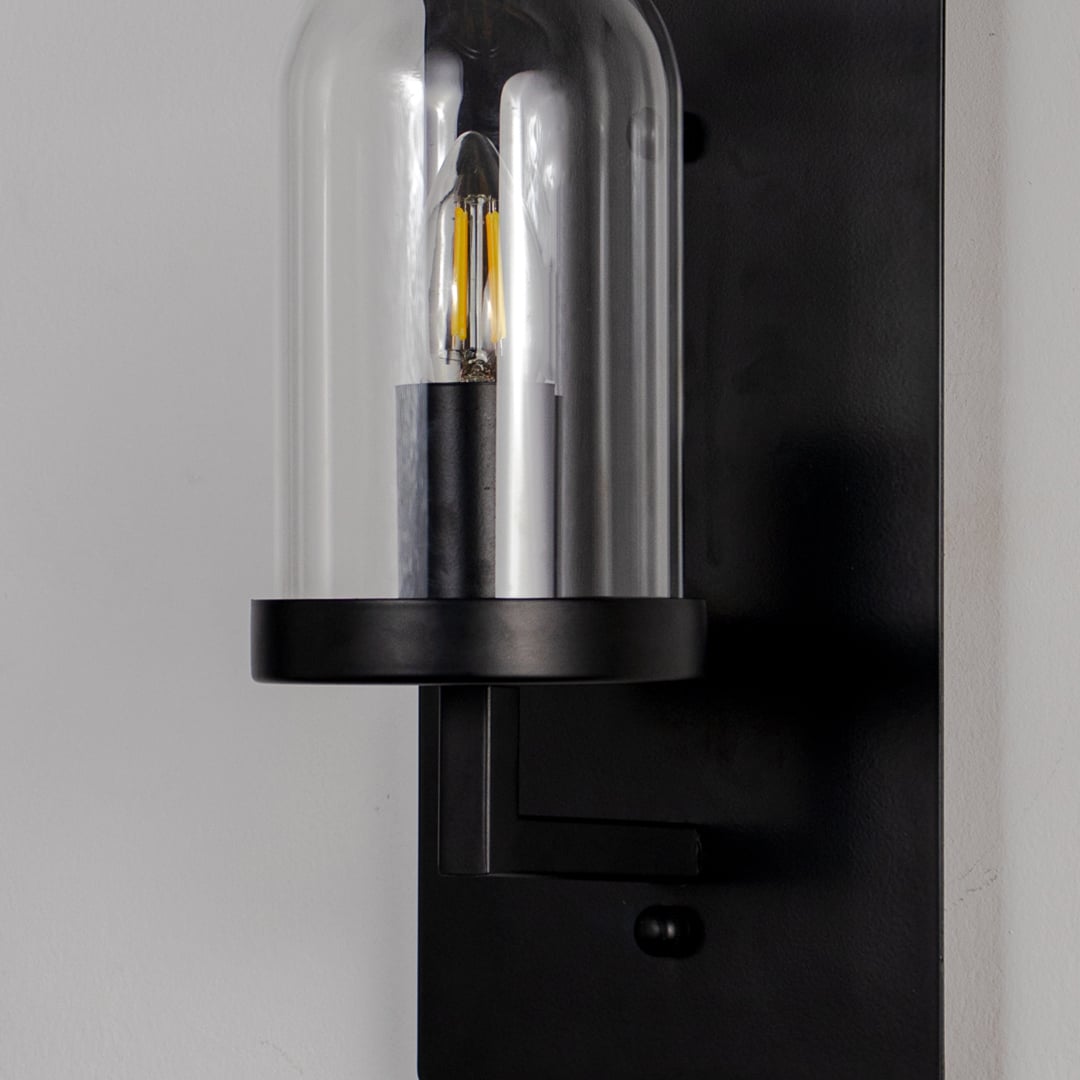 Closeup of black metal wall light with clear glass shade for modern hallway and luxury decor styling spaces.