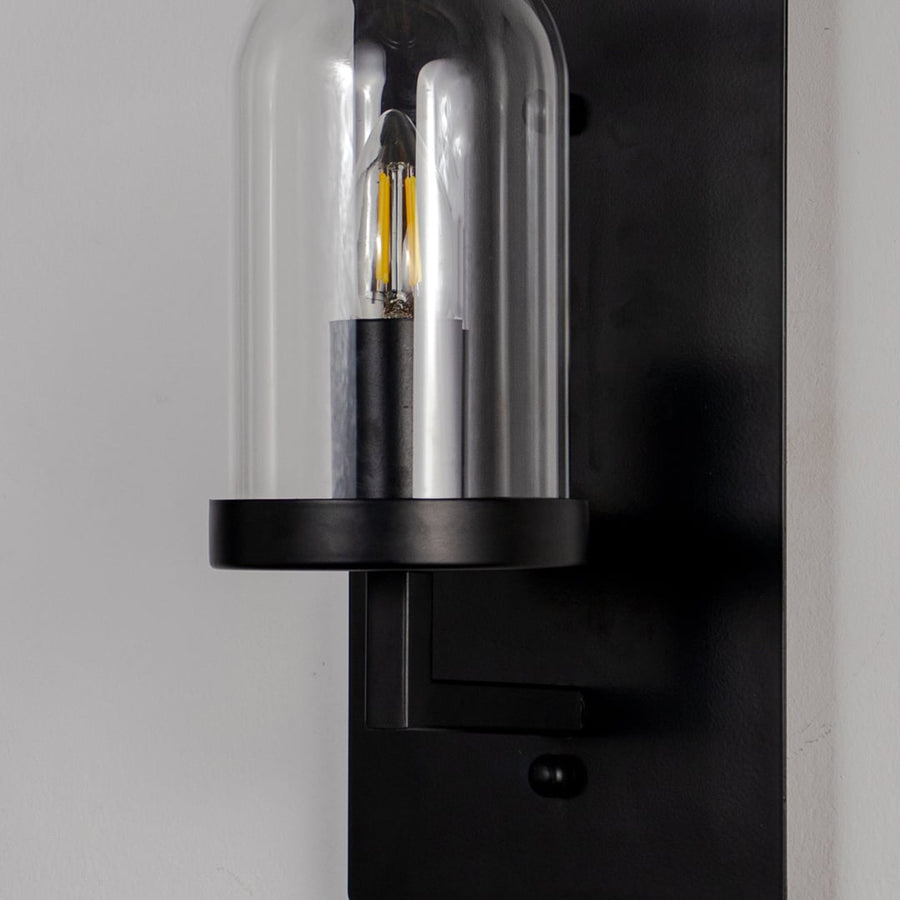 Closeup of black metal wall light with clear glass shade for modern hallway and luxury decor styling spaces.