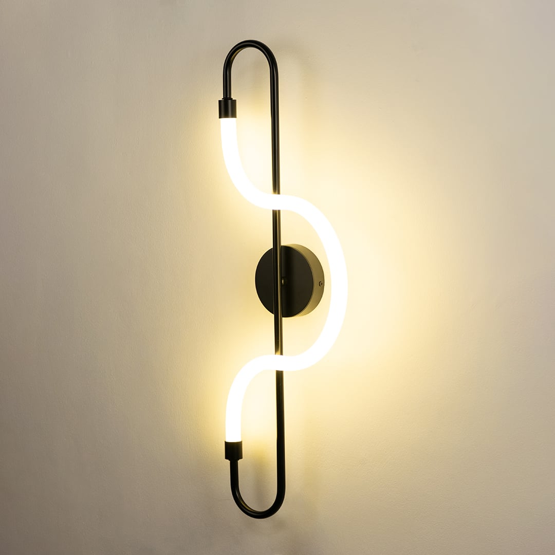 A stylish black metal LED wall lamp glowing brightly on a clean white wall perfect for decorative ambient lighting in contemporary interiors.