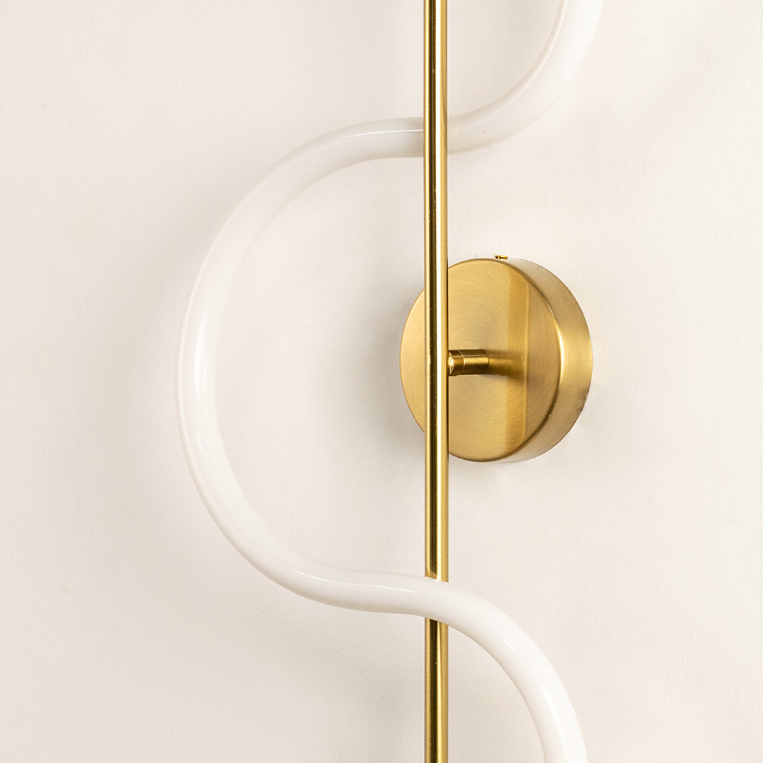 Closeup of gold metal wall light with frosted acrylic diffuser for elegant modern hallway and bedroom decor styling.