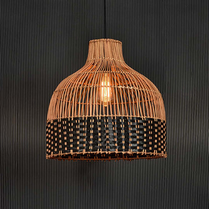 Rattan pendant light illuminated on black background radiating a warm glow through its two-tone woven design.