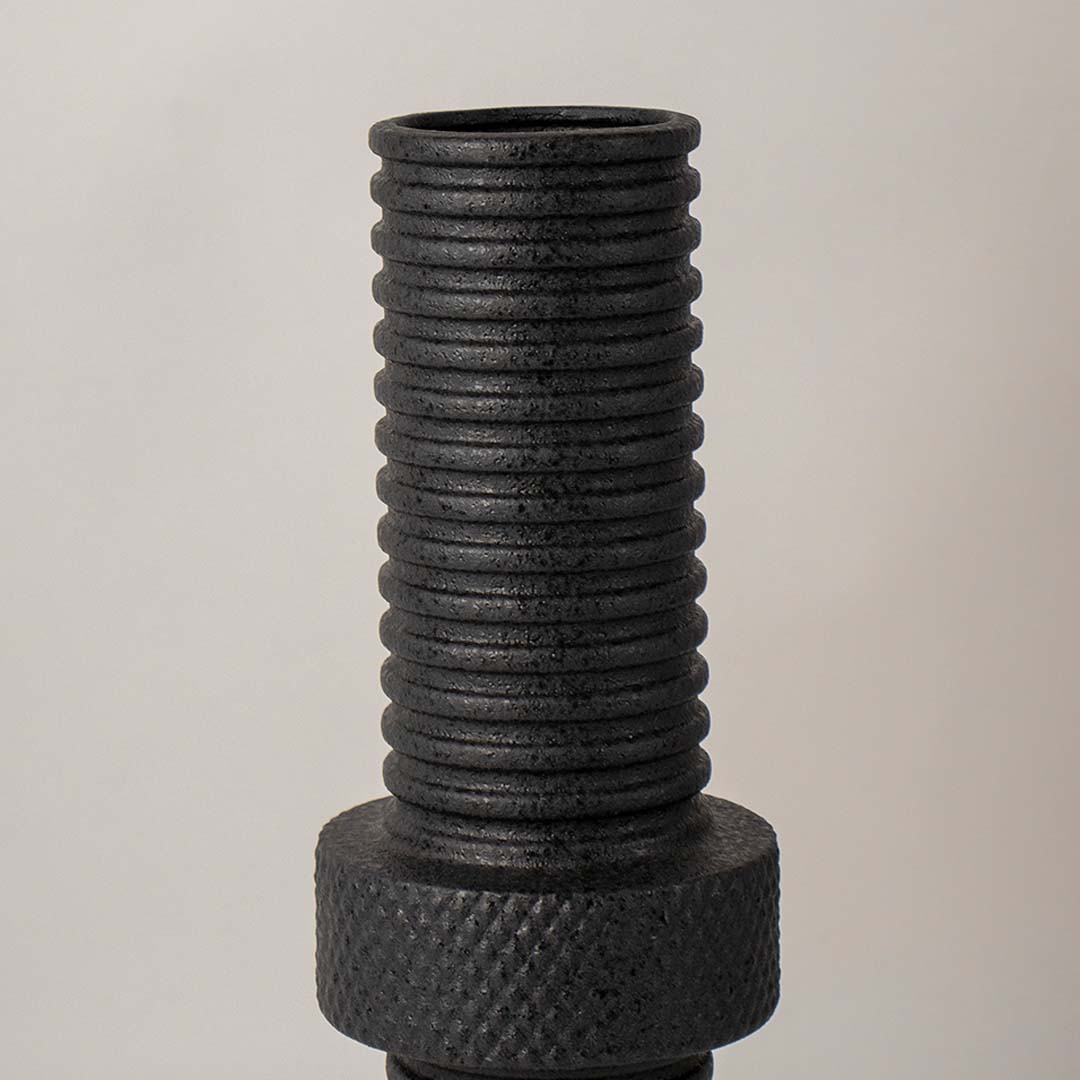 Detailed closeup of black ribbed metal vase showing its textured matte surface and fine handcrafted industrial finish.