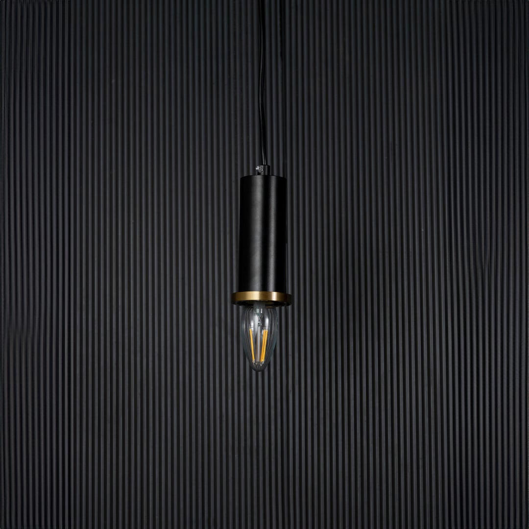 Black and gold pendant light on black background with light off is a modern cylindrical hanging lamp design.