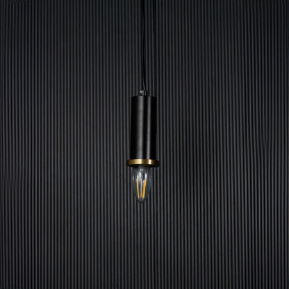 Black and gold pendant light on black background with light off is a modern cylindrical hanging lamp design.