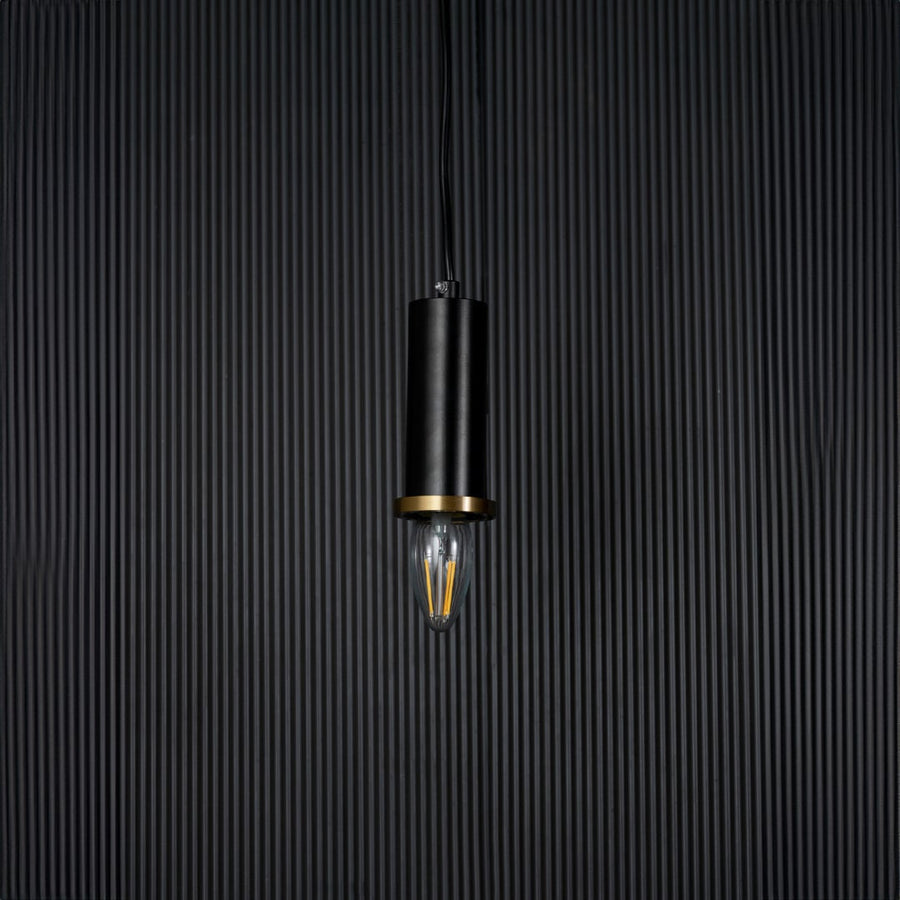 Black and gold pendant light on black background with light off is a modern cylindrical hanging lamp design.