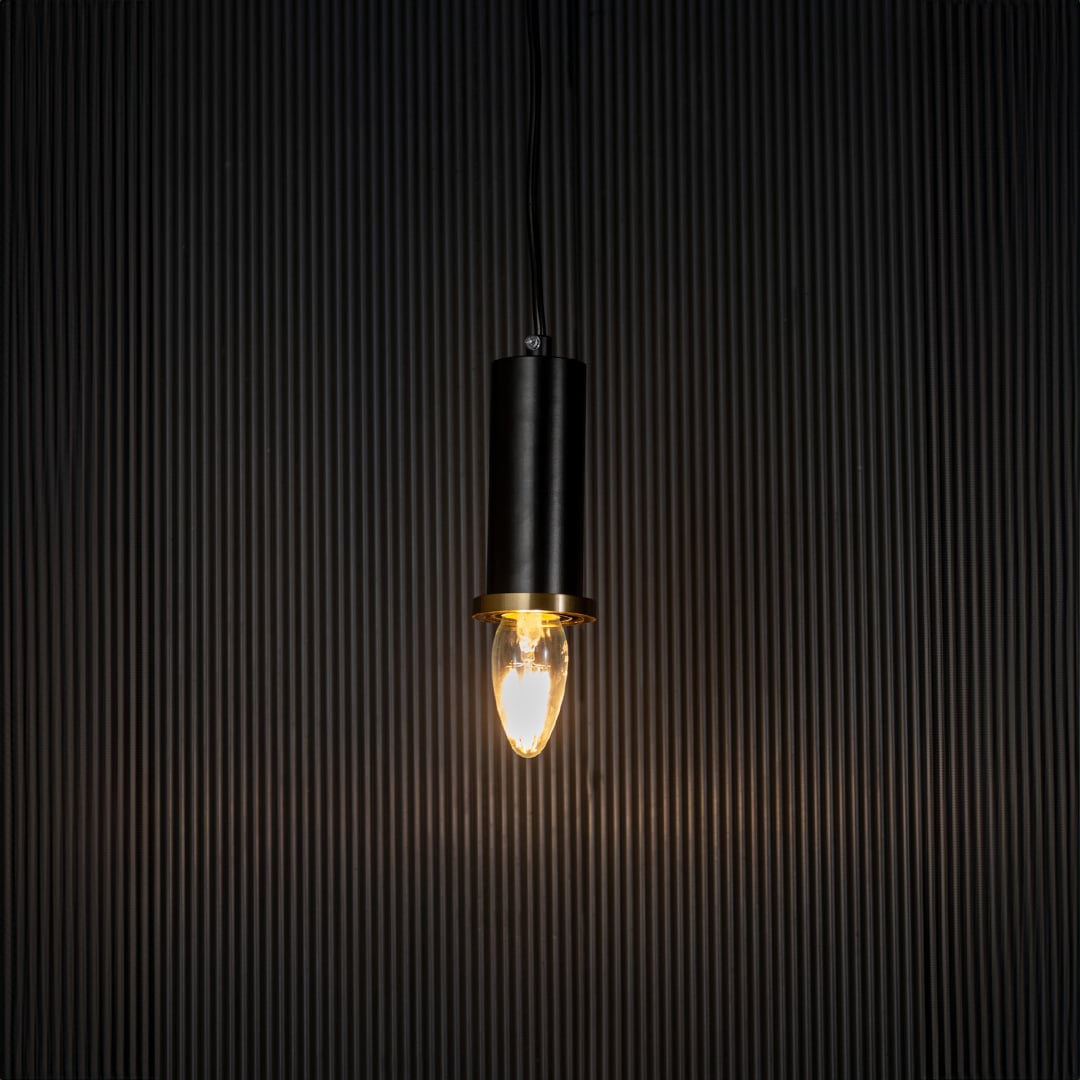 Black and gold pendant lamp on black background is an elegant cylindrical ceiling light for modern spaces.