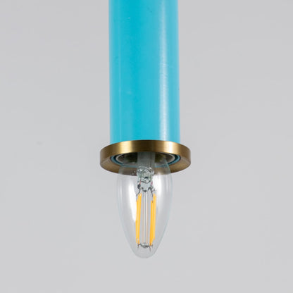 Closeup of blue pendant light with brass ring and clear bulb turned on showing detailed ceiling decor design.