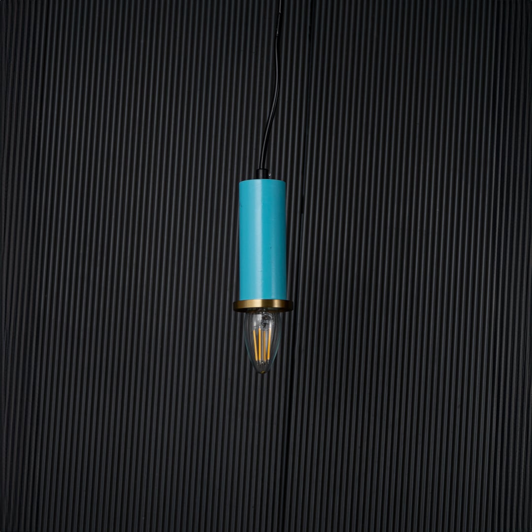 Blue pendant light turned off with brass accent and bulb shown as elegant ceiling decor on black background.