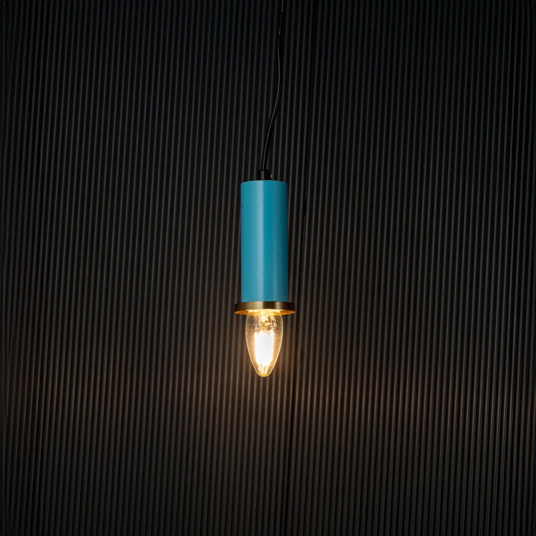 Elegant blue pendant light turned on with warm glow creating ambient ceiling lighting on black background.