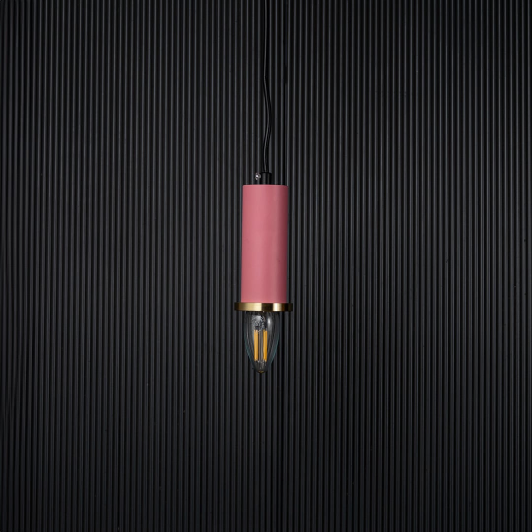 Pink pendant light turned off with brass accent and bulb shown as modern hanging decor on black background.