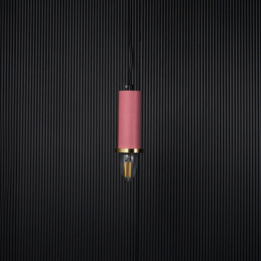 Pink pendant light turned off with brass accent and bulb shown as modern hanging decor on black background.