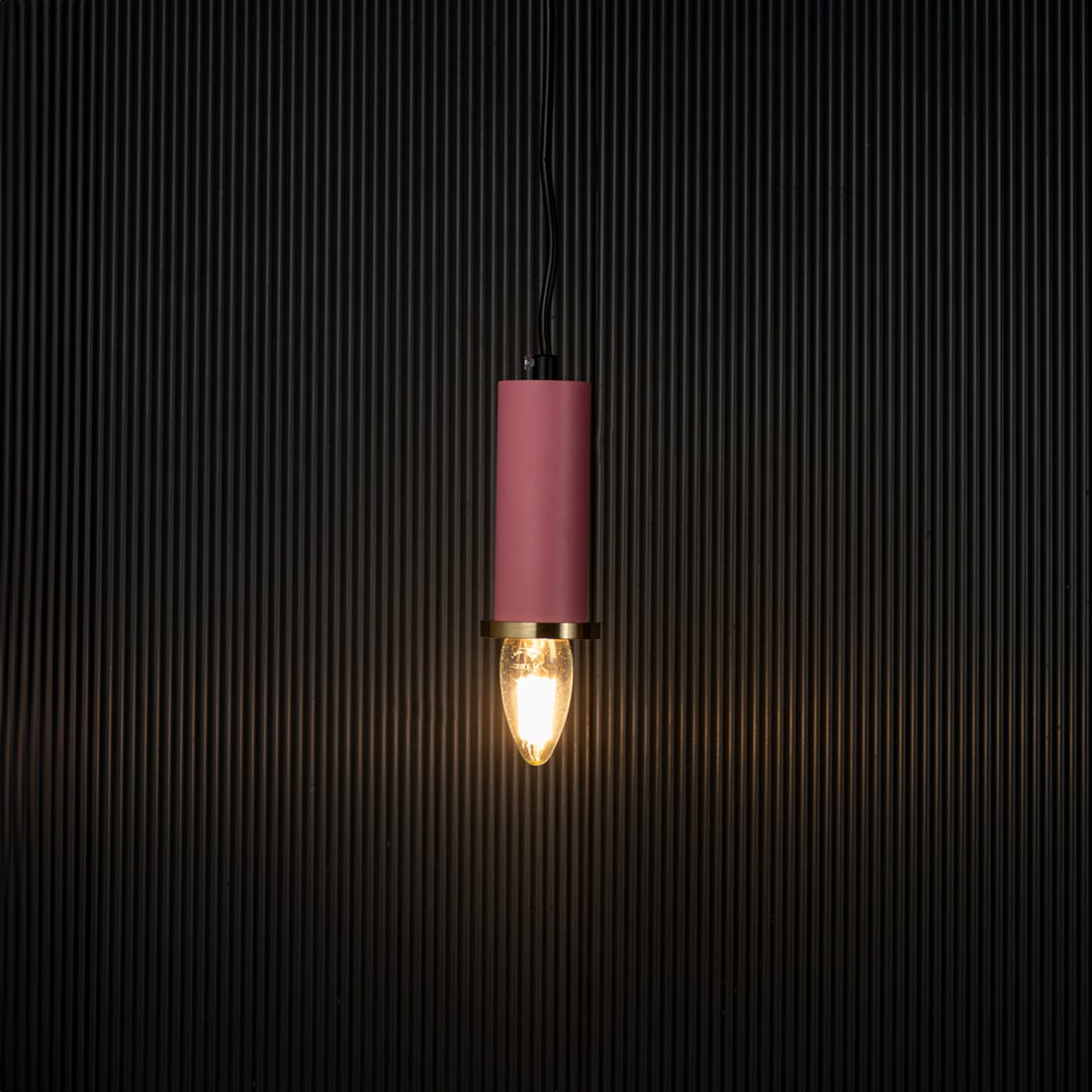 Elegant pink pendant light turned on with warm glow creating ambient lighting effect on black background.