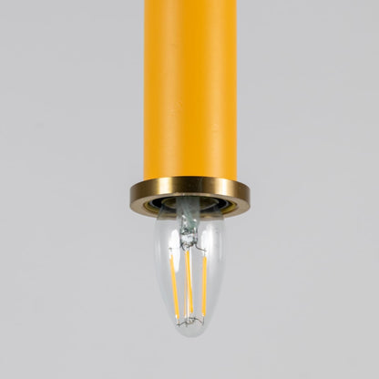 Closeup of yellow pendant light with brass ring and clear bulb turned on showing detailed ceiling decor design.