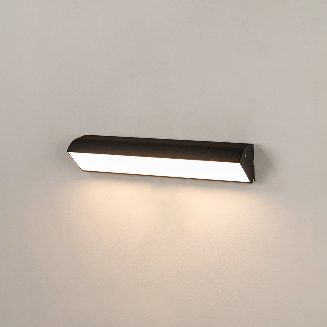 Minimalist black aluminum outdoor LED wall bar light on white background casting downward illumination for porch decor.