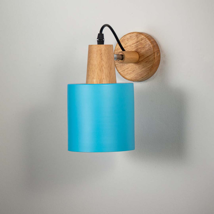 Blue metal wall light with wooden mount and black arm on neutral background modern cone shade design perfect for bedside lighting decor.