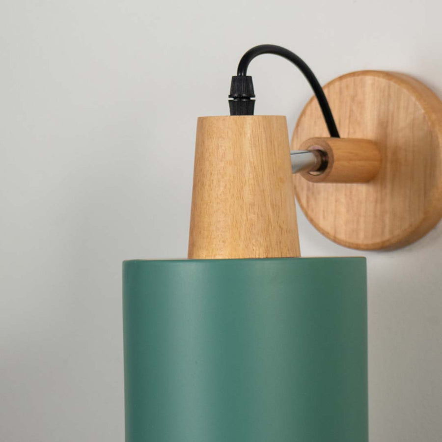 Green metal wall light with wooden mount and black arm on neutral background modern cone shade lighting ideal for bedroom and living room decor.