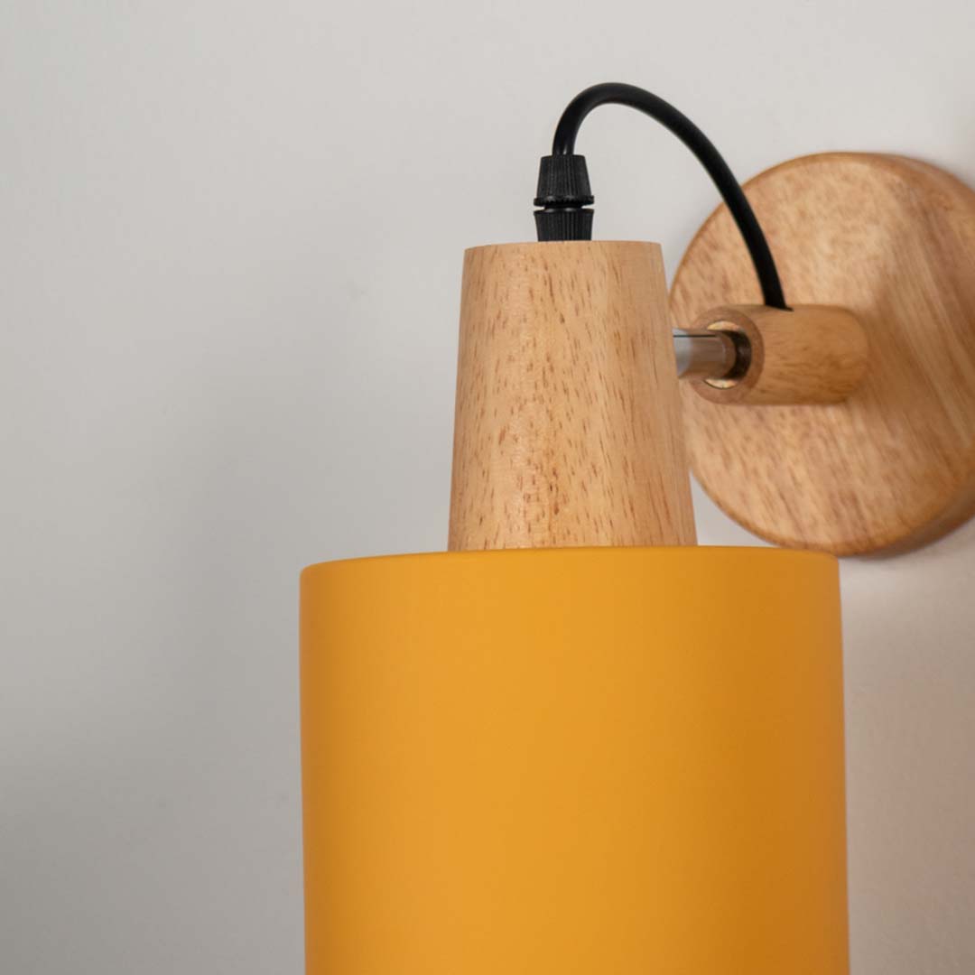 Yellow metal wall light with wooden mount and black arm on neutral background modern cone shade ideal for bedroom lighting decor.

