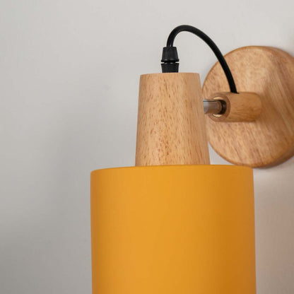 Yellow metal wall light with wooden mount and black arm on neutral background modern cone shade ideal for bedroom lighting decor.

